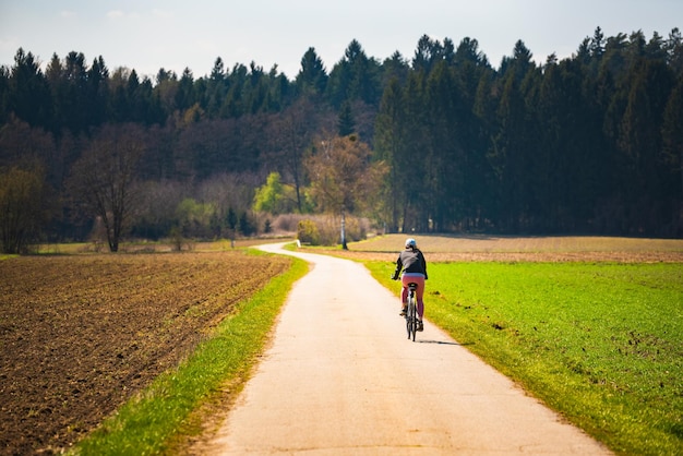 Ragazza in bicicletta sulla strada rurale che porta alla foresta