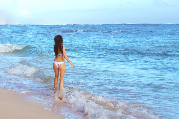 Ragazza in bikini bianco sulla spiaggia