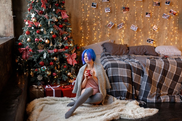 Ragazza in camera da letto vicino all'albero di Natale nel nuovo anno a casa