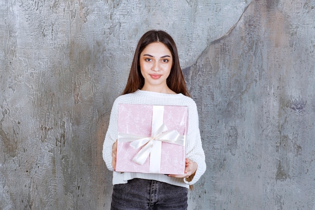 Ragazza in camicia bianca che tiene una confezione regalo viola.