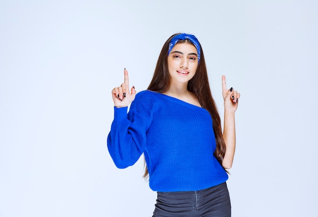 Ragazza in camicia da festa blu che presenta qualcosa sopra.