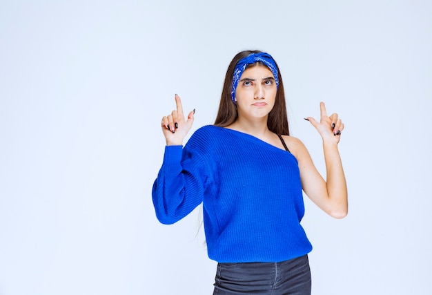 Ragazza in camicia da festa blu che presenta qualcosa sopra.