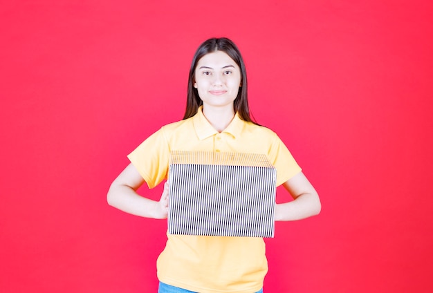 Ragazza in camicia gialla con scatola regalo d'argento.