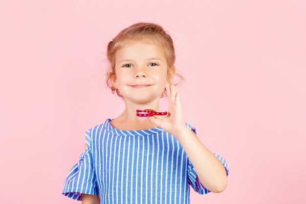 Ragazza in camicia spogliata blu sta giocando a spinner rosso in mano