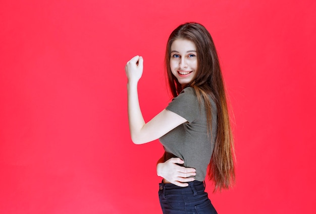 Ragazza in camicia verde che dimostra i suoi muscoli del braccio.