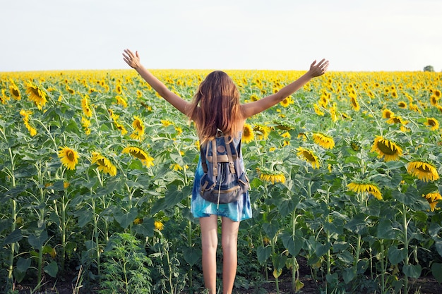 Ragazza in campo di girasole, una ragazza emotiva, una ragazza entra in un campo di girasoli, vista da dietro; copia spazio