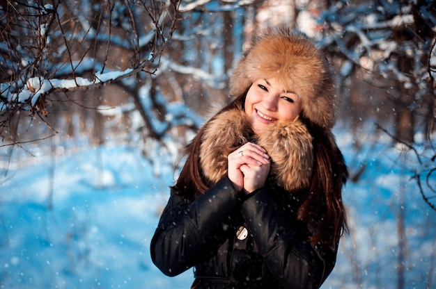 Ragazza in cappello caldo con paraorecchie sullo sfondo della neve