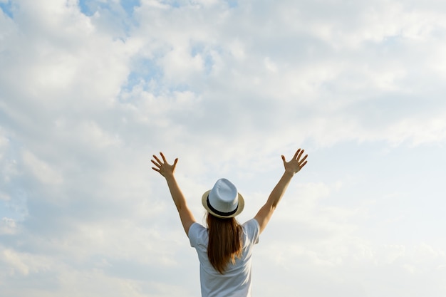 Ragazza in cappello con le mani in su