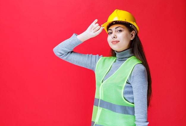 Ragazza in casco giallo che tiene il suo casco e posa.