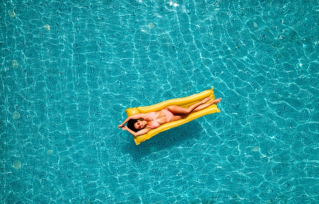 Ragazza in costume da bagno che si abbronza in piscina