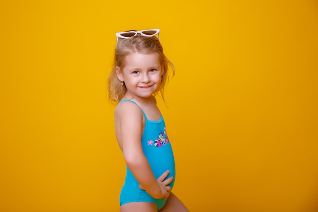 Ragazza in costume da bagno e occhiali da sole su giallo