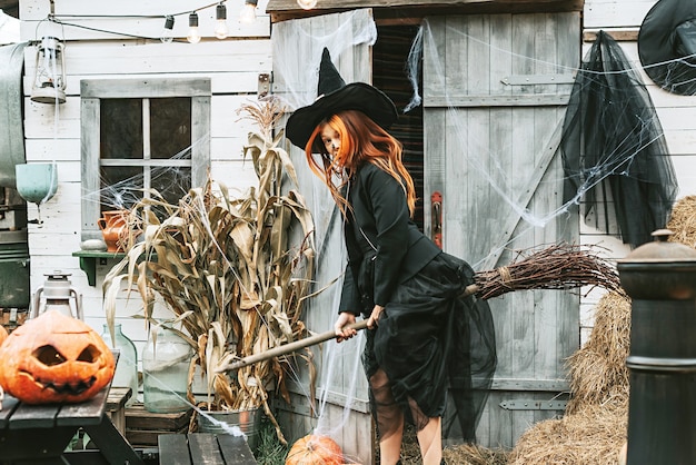 Ragazza in costume da strega con una scopa a una festa di Halloween