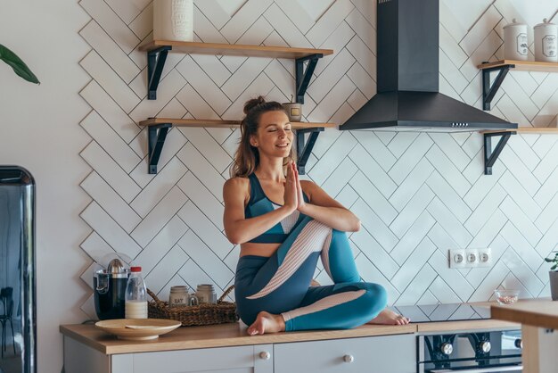 Ragazza in cucina meditando la pratica dello yoga.