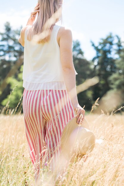 Ragazza in culottes a strisce con un cappello di paglia in mano