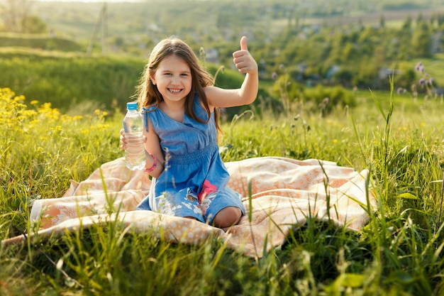 Ragazza in erba con la bottiglia di acqua di plastica