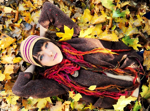 Ragazza in foglie d'autunno