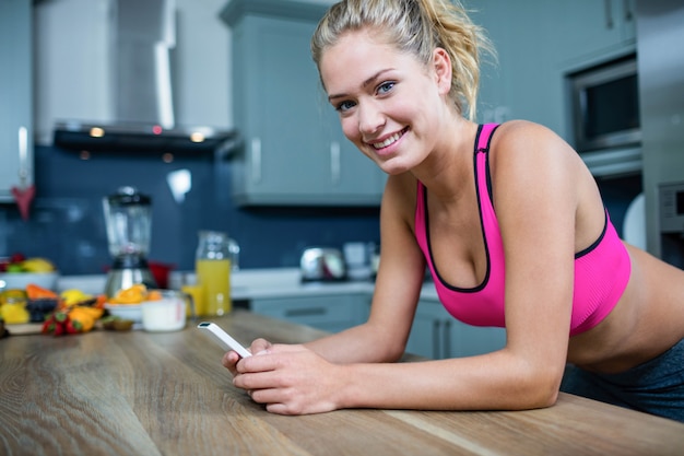 Ragazza in forma che invia messaggi di testo in cucina