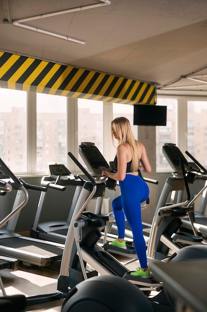 Ragazza in forma in classe di aerobica Donna muscolare sexy con corpo snello che corre nella palestra vuota Signora che fa allenamento in palestra moderna