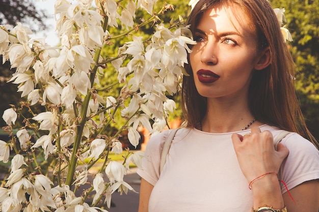 Ragazza in giardino al tramonto con fiori bianchi