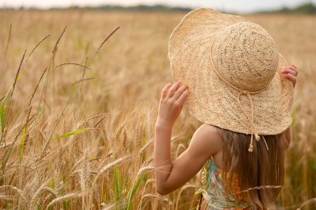 ragazza in grande cappello di paglia sul campo agricolo