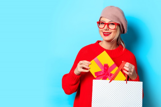 Ragazza in maglione rosso con confezione regalo e shopping bag