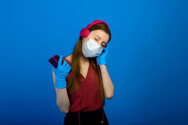 Ragazza in maschera medica protettiva e guanti blu su sfondo blu. Ritratto di Close-up di una donna in una maschera trasparente.