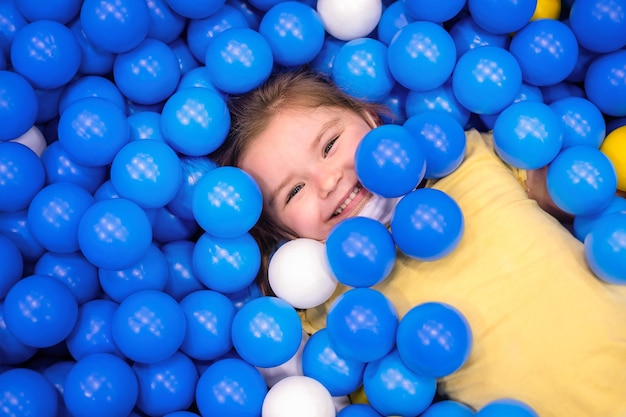 Ragazza in palla multicolore in gruppo giochi per bambini.