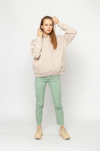 Ragazza in pantaloni cargo verdi e felpa con cappuccio beige isolata su bianco