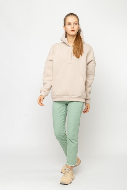 Ragazza in pantaloni cargo verdi e felpa con cappuccio beige isolata su bianco