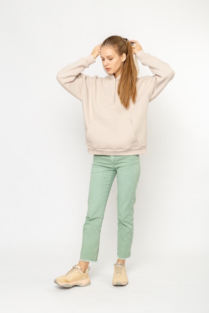 Ragazza in pantaloni cargo verdi e felpa con cappuccio beige isolata su bianco