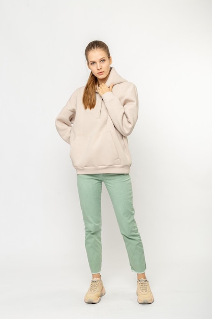 Ragazza in pantaloni cargo verdi e felpa con cappuccio beige isolata su bianco