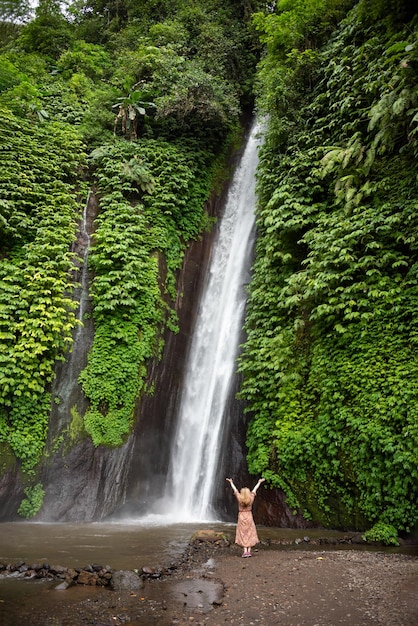 Ragazza in piedi davanti alla grande cascata nella foresta tropicale di Bali Indonesia