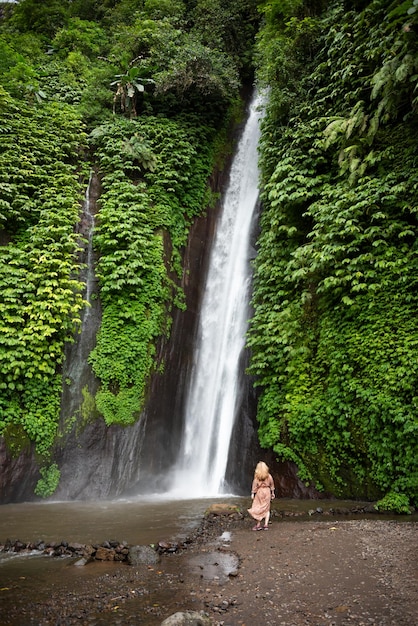 Ragazza in piedi davanti alla grande cascata nella foresta tropicale di Bali Indonesia