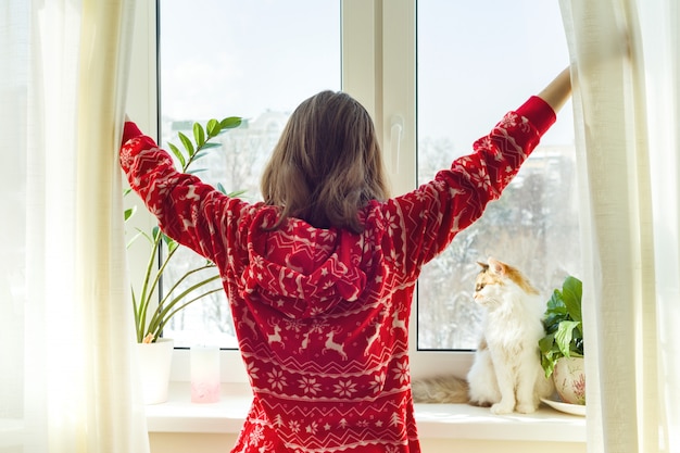 Ragazza in pigiama caldo di inverno con il gatto