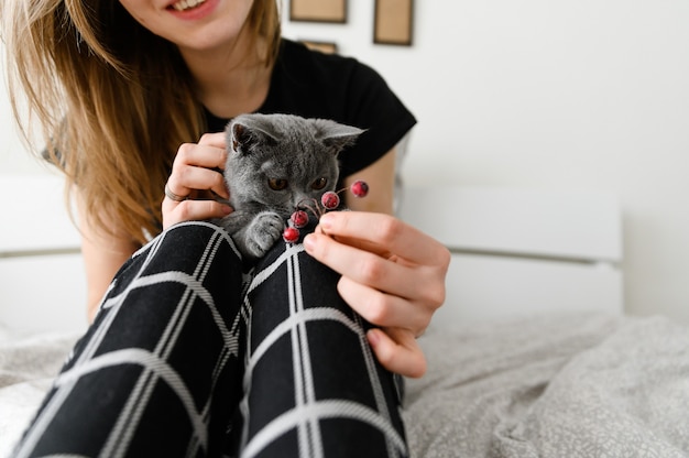 ragazza in pigiama tiene il suo amato animale domestico tra le braccia. Gattino scozzese tra le braccia della ragazza.