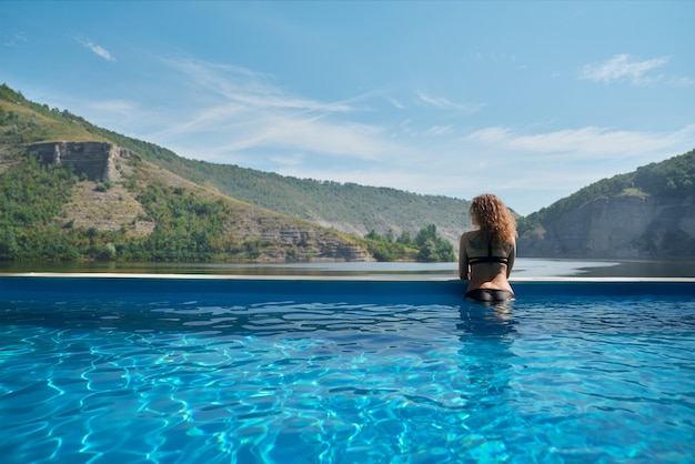 Ragazza in piscina ammirando il paesaggio.