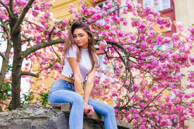 Ragazza in posa con fiori di ramo all'esterno