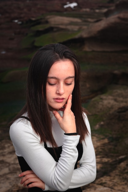 Ragazza in posa con un abito bianco e nero in una baia rocciosa della costa basca.