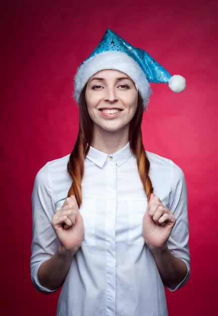 Ragazza in posa in studio su sfondo rosa in un cappello di Natale