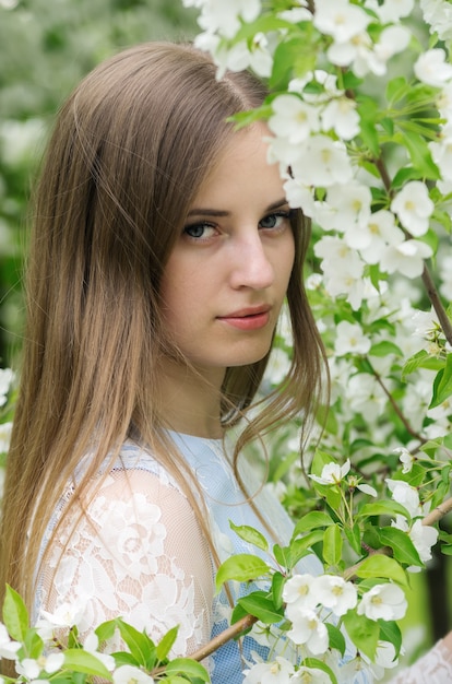 Ragazza in posa su uno sfondo di alberi in fiore