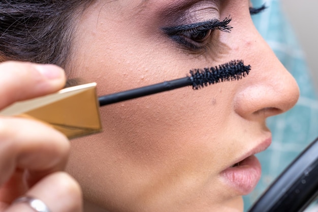 Ragazza in possesso di fodera trucco cercando in mano specchio Attraente ragazza naturale applicando eyeliner in possesso di uno specchio