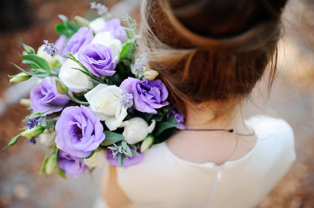 Ragazza in possesso di un bouquet da sposa di fiori bianchi e viola