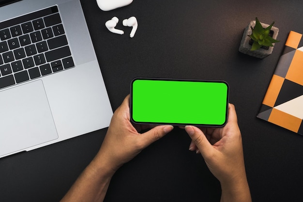 Ragazza in possesso di uno smartphone con schermo verde su sfondo nero tavolo Ambiente d'ufficio Chroma Key