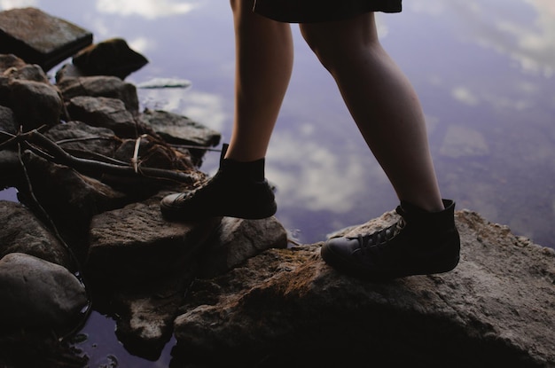 Ragazza in scarpe da ginnastica che cammina sulle rocce sul lago