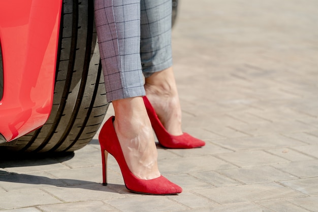 Ragazza in scarpe rosse e un'auto rossa in una giornata di sole estivo.