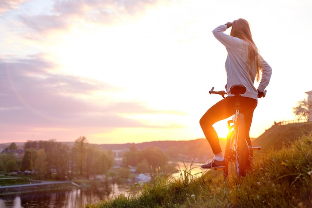 Ragazza in sella a bici nel tramonto