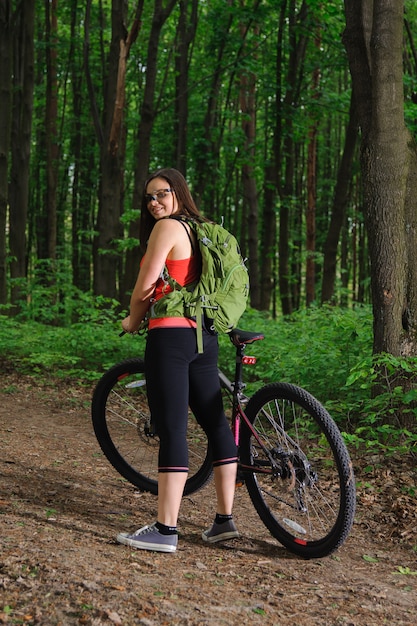 Ragazza in sella a una bicicletta nel bosco