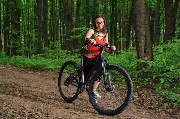 Ragazza in sella a una bicicletta nel bosco