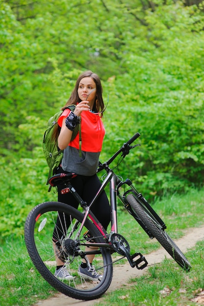 Ragazza in sella a una bicicletta nel bosco