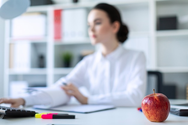 Ragazza in ufficio con una mela. Una fotografia con una profondità di campo, un focus evidenziato su una mela.